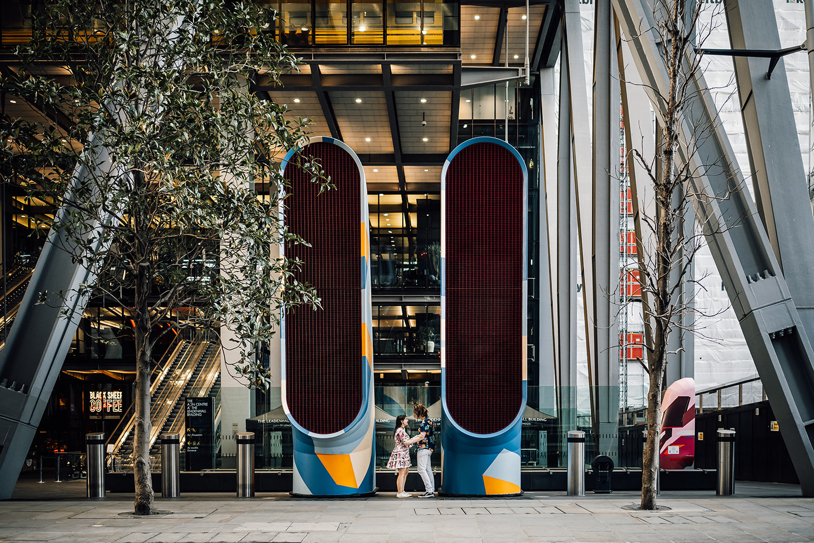 Tiryon and Isobel together between two colourful architectural columns