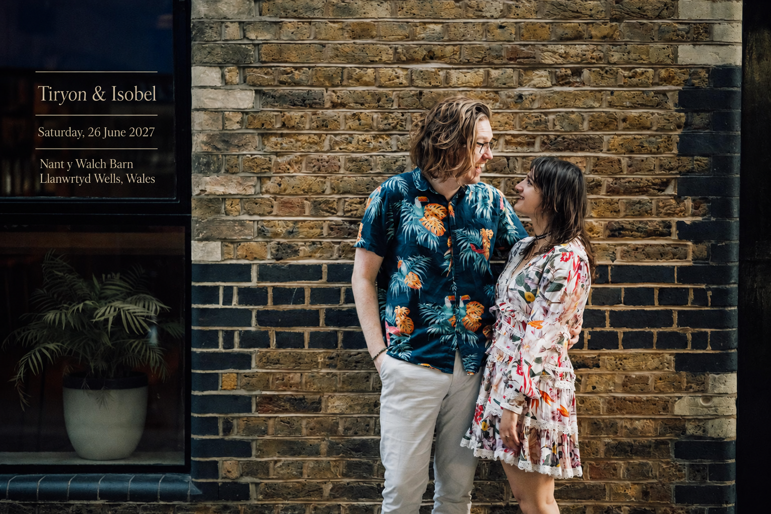 Tiryon and Isobel beside a sign showing their wedding date and venue